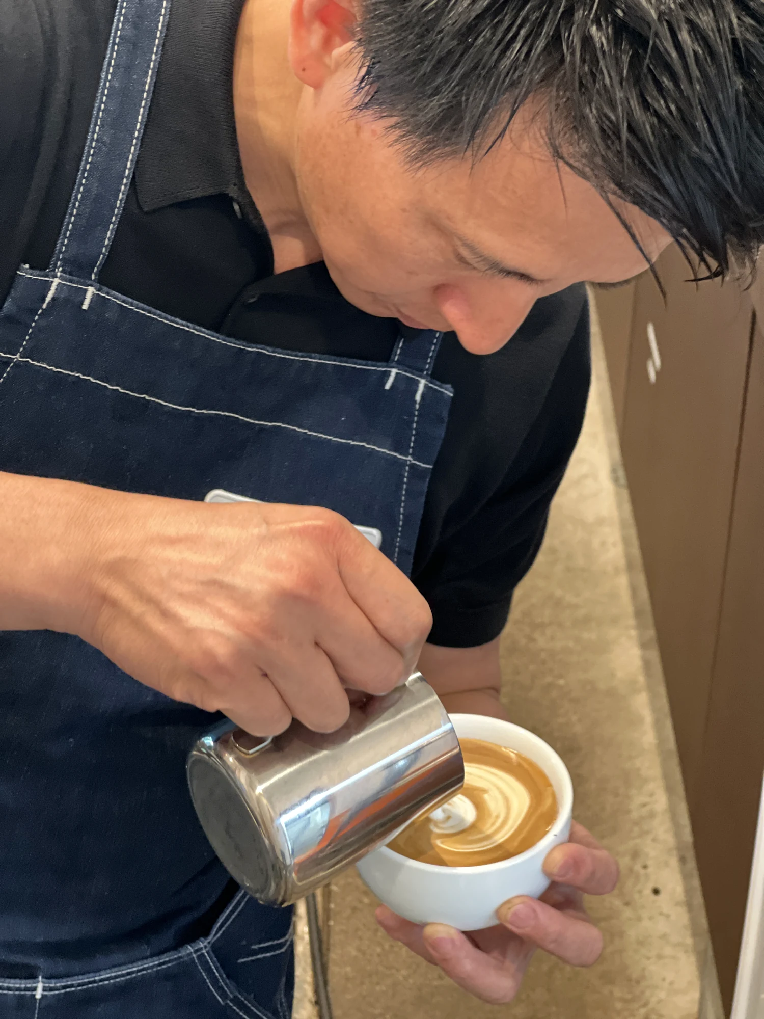 ラテを注ぐ手元。カフェさんびお、2024年6月。