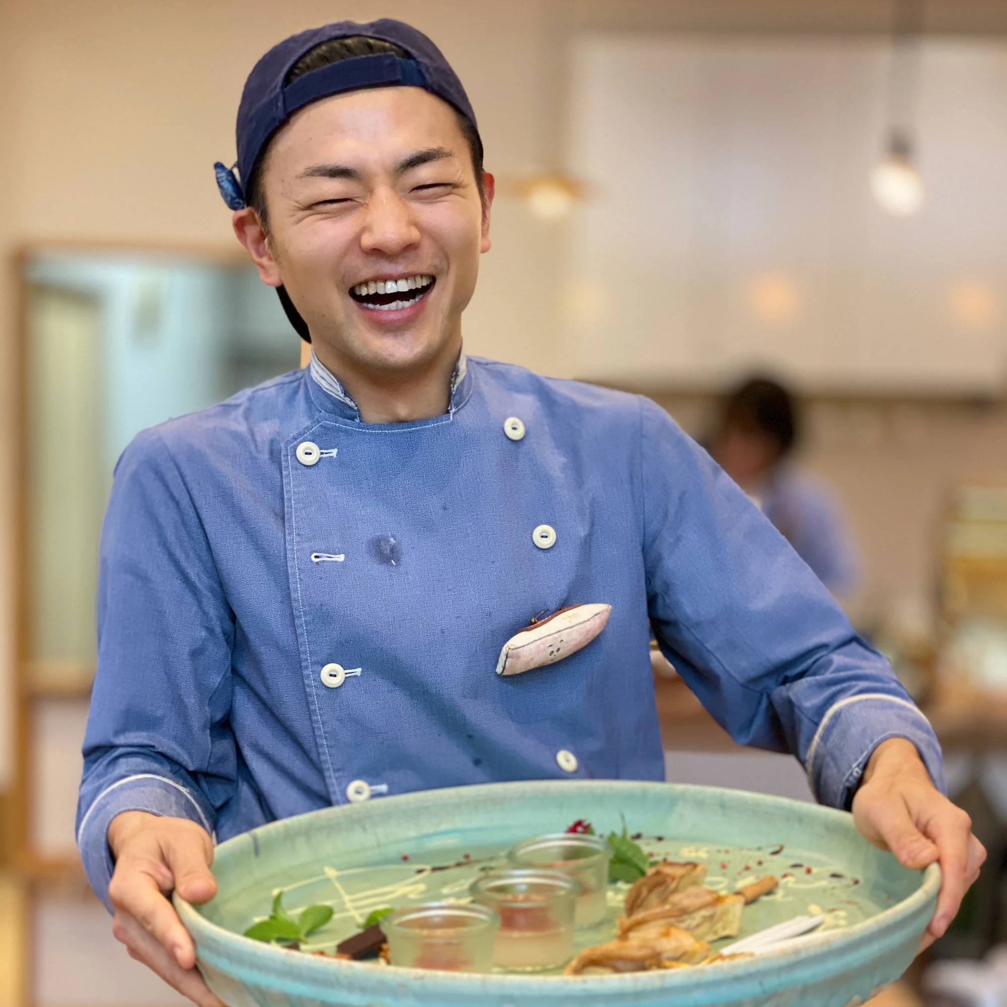 大皿を持って笑う本人。コックコート